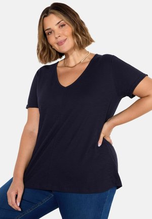 T-shirt blu navy a maniche corte con scollo a V, vestibilità comoda, tessuto morbido e dettaglio di cucitura verticale; abbinato a jeans di denim.