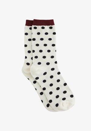 Chaussettes blanches avec un bord côtelé bordeaux, ornées d'un motif de pois noirs uniformément espacés. Tissu doux avec une texture lisse.