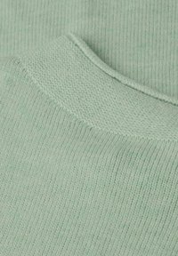 Gros plan sur un tissu tricoté vert clair montrant des motifs de points côtelés et texturés avec des bords pliés.