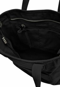 Interno di una borsa a tracolla nera con tessuto morbido, tasca con zip e sezione organizer. Caratterizzata da manici robusti e dettagli in metallo.