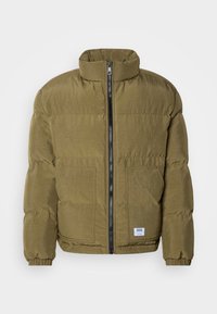 Giacca imbottita verde oliva con colletto alto, zip frontale e due grandi tasche anteriori. Presenta polsini elasticizzati e un tessuto texturizzato.