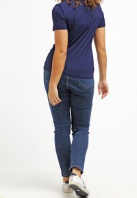 Navy short-sleeve shirt paired with blue skinny jeans. The shirt has a smooth texture, and the jeans feature a classic denim look. White sneakers complete the outfit.