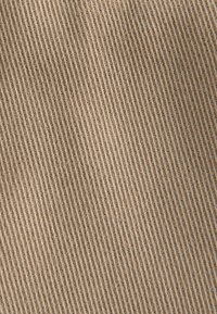 Beige corduroy fabric with vertical ridges, showcasing a soft texture and even, consistent pattern across the surface.