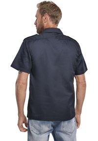 Camicia corta a manica di colore blu navy con colletto, texture liscia e vestibilità su misura, caratterizzata da un design posteriore pulito e senza loghi o fantasie visibili.