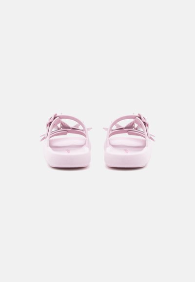 Ζευγάρι πλατφόρμες σανδάλια σε ανοικτό ροζ χρώμα με πίσω λουριά και διακοσμητικό φιόγκο, παρουσιάζονται από πίσω σε λευκό φόντο.