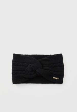 Bandeau en maille noir avec un devant torsadé et petit logo doré HUGO, présenté sur fond blanc.