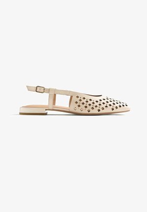 Zapato plano beige con tira en el talón, recortes cuadrados en la parte delantera, correa ajustable con hebilla y tacón rectangular bajo sobre fondo blanco.