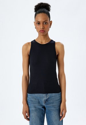 Zwarte geribde tanktop met een ronde hals en mouwloos design, gecombineerd met lichtblauwe denim jeans. Zachte textuur en aansluitende pasvorm.