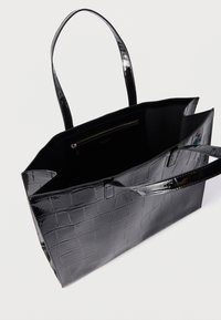 Fekete lakkbőr bevásárlótáska krokodilmintával, két fogantyúval és belső cipzáras zsebbel. Tágas és merev kialakítás.