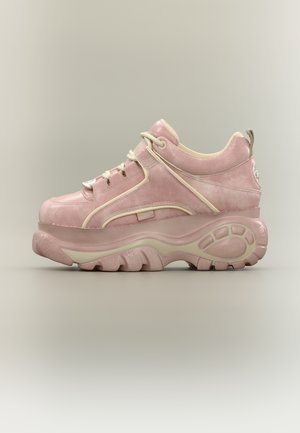 Ružová semišová platformová teniska s hrubou textúrovanou podrážkou, krémové šnúrky a béžový lem na jednoduchom sivom pozadí.