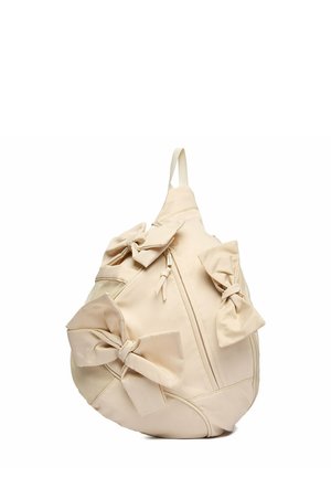 Beigefarbener, tropfenförmiger Rucksack mit drei großen Stoffschleifen, vordere Reißverschlusstasche, Netzseitentasche und einem einzelnen oberen Griff.