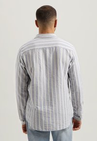 Striped langermet skjorte i lys blå og hvit, med kontrasterende tynne og tykke striper, knappede mansjetter og en lett buet kant.