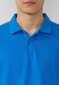 Blauwe polo shirt van katoen met een gestructureerde weefsel. Voorzien van een klassieke kraag, een twee-knopen placket en een geborduurd logo op de borst.