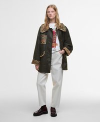 Green jacket with floral embroidered collar and cuffs, featuring a front pocket and buttons, paired with white trousers and dark shoes.