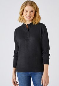 Zwart gebreide trui met een henley-halslijn, drie-knopen placket en gebreide manchetten. Heeft een getailleerd ontwerp en een zachte textuur.