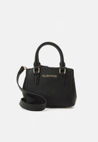 Sort håndveske laget av teksturert skinn med gullfarget beslag, to håndtak og en justerbar skulderreim. Har logo på forsiden.