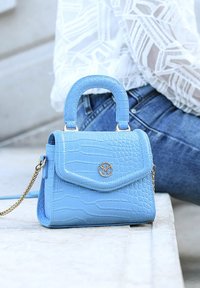 Blå handväska i konstläder med krokodilstruktur, beslag i guldton, handtag upptill och avtagbar kedjesnodd. Har en vikbar klaff.