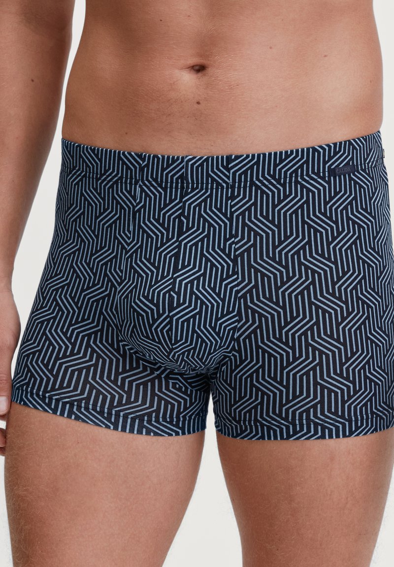 Marineblauwe boxershorts met een geometrisch wit patroon, gemaakt van rekbaar materiaal. Kenmerkt zich door een comfortabele tailleband en een nauwsluitend ontwerp.