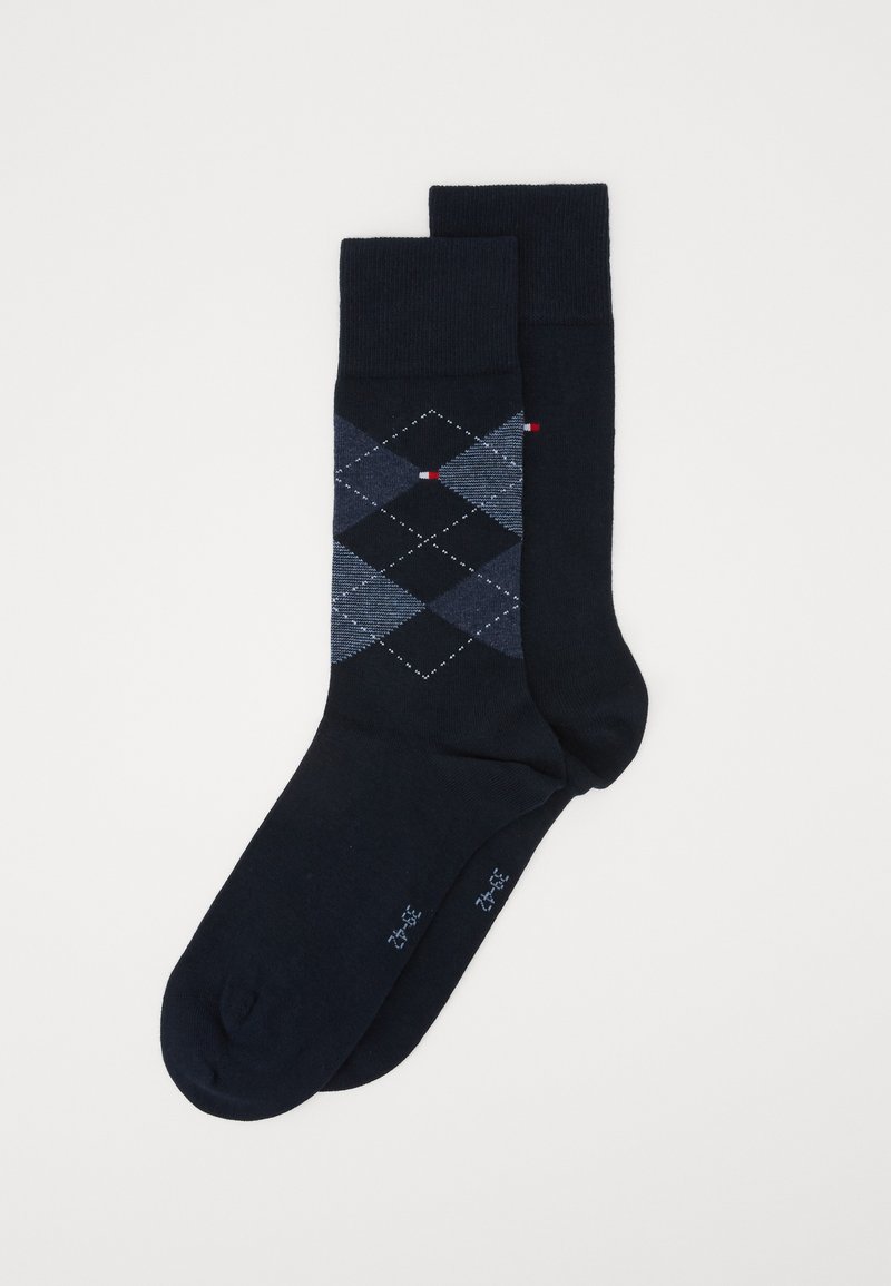 Marineblaue Socken mit einem Rautenmuster in verschiedenen Blautönen, verziert mit roten und weißen Akzenten. Hergestellt aus einem weichen, dehnbaren Material.