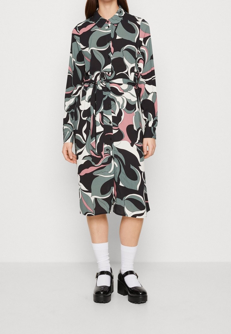 Košilové šaty vyrobené z lehké látky s barevným abstraktním vzorem listů v černé, zelené, bílé a růžové barvě. Obsahuje pásek.