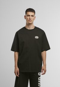 Black cotton short-sleeve t-shirt with a round neckline, featuring a white bear logo on the left chest. The fabric appears smooth.