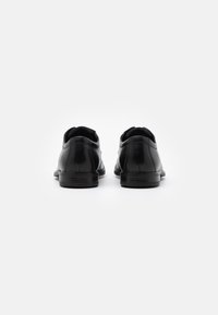 Black leather shoes with a smooth finish, rounded toe, low heel, and backless design. Minimal stitching and simple silhouette.
