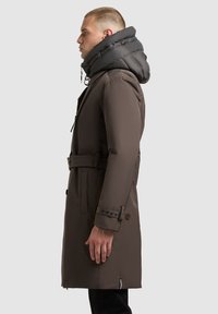 Brown trench coat with a padded black hood, belted waist, and buttoned cuffs. Side view shows sleek design and structured silhouette.