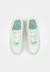Sneakers Nike Air w miętowo-zielonym i białym skórzanym kolorze, z perforowanym czubkiem, płaskimi białymi sznurowadłami i lekko wyściełaną wkładką z logo.