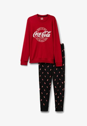 Roter Sweatshirt mit weißem Coca-Cola-Logo, kombiniert mit schwarzen Hosen, die verstreute Grafiken von roten Coca-Cola-Dosen aufweisen. Das Set besteht aus weichem Stoff.