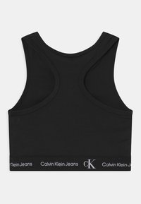 Czarny krótki top na ramiączkach z zaokrąglonym dekoltem i szerokimi paskami. Posiada markową elastyczną taśmę na dole z białym napisem. Gładka tekstura.