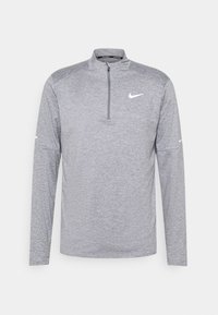 Harmaa pitkähihainen Nike-paita, jossa on neljännesvetoketjukaulus, pehmeä tekstuuri ja logo rinnassa ja hihassa, urheilullinen ja kapea muotoilu.