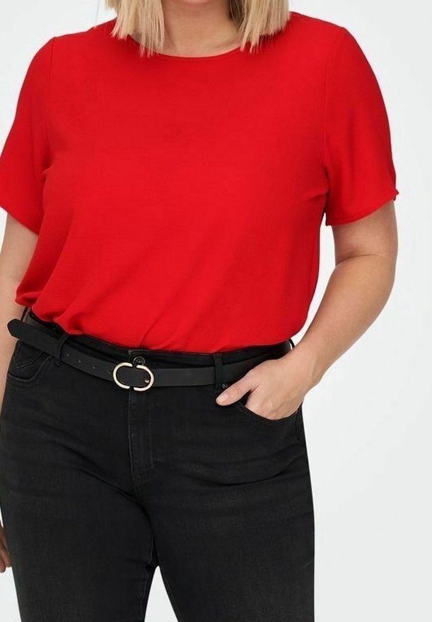 Camiseta roja de manga corta hecha de tela suave, combinada con unos vaqueros negros de cintura alta y un cinturón negro estrecho con una hebilla circular dorada.