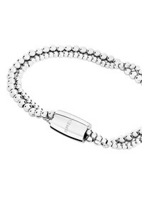 Hopeaketju, jossa on hopeansävyisiä helmiä, koostuu kahdesta paksusta metallihelistä, jotka on yhdistetty sileällä, suorakaiteen muotoisella soljella, jossa on kaiverrettu brändimerkintä.