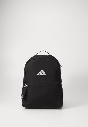 Mochila negra con un tejido suave, forma redondeada, bolsillo con cremallera en la parte frontal, bolsillo de malla en el lateral y un logo plateado de Adidas en la parte delantera.