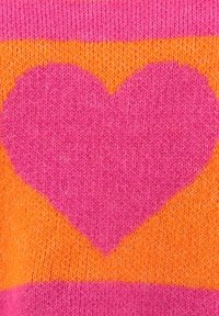 Tissu tricoté avec une grande forme de cœur rose centrée sur un fond orange, bordée de bandes roses en haut et en bas.