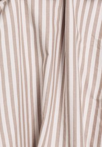 Katoenen stof met afwisselende verticale strepen in beige en wit, met een gladde textuur en een lichte glans.