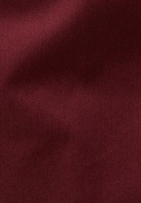 Tessuto bordeaux con una texture liscia e leggermente lucida e un motivo di tessitura diagonale. Nessun accento o hardware visibile.