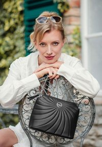 Černá prošívaná kabelka se vzorem ve spirále, stříbrným řetězovým popruhem a akcentem loga. Hladký povrch a obdélníkový tvar.