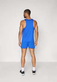 Top desportivo azul sem mangas e calções, feitos de tecido leve. O top apresenta um design sem mangas; os calções são de comprimento acima do joelho.