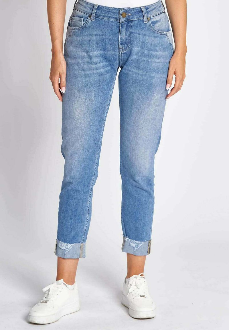 Hellblaue Denim-Jeans mit schmalem Schnitt, umgeschlagenen Säumen, fünf Taschen, Messingknopfverschluss und dezentem Verblassen des Stoffes.