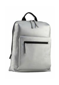 Sac à dos argenté en matériau synthétique lisse ; dispose d'une poche zippée à l'avant et de deux poignées supérieures, avec un design minimaliste.