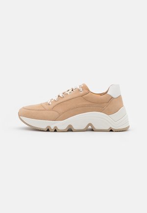 Beige Wildlederschuh mit einer weißen Ferse und einer strukturierten Gummisohle. Verfügt über runde Schnürsenkel und eine abgerundete Zehenpartie mit einem flachen, niedrigen Design.