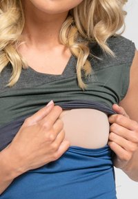 Multicolored shirt in gray, teal, and navy, featuring a V-neck design. A portion is lifted to reveal a nude undergarment with smooth texture.