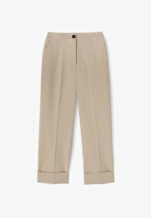 Beige, op maat gemaakte broek met voorplooien, zijzakken, omgeslagen pijpen en een zwarte knoopsluiting bij de tailleband.