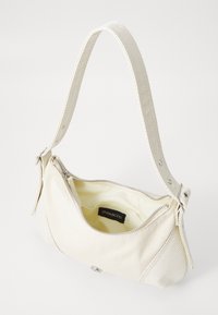White canvas handbag with a textured strap and a zip closure. Features a smooth interior lined with fabric, showcasing the brand label inside.