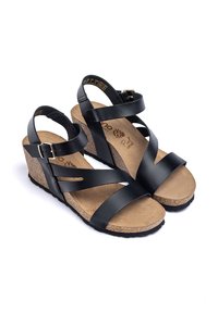 Sandali con tacco nero, suola in sughero, con cinturini in pelle incrociati e fibbia regolabile alla caviglia. Morbido rivestimento della soletta beige.