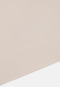 Tapis de table en silicone de couleur beige doux, arborant le nom de la marque en relief et des symboles d'entretien. Texture lisse avec des bords arrondis, conçu pour un usage pratique.