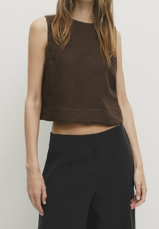 Haut marron raccourci sans manches en tissu texturé. Présente un col rond et un ourlet droit, associé à un pantalon noir à jambes larges.