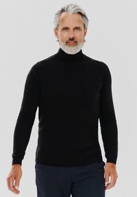 Czarny sweter z golfem, wykonany z miękkiego materiału, z dopasowanym krojem i długimi rękawami, w połączeniu z ciemnymi spodniami.