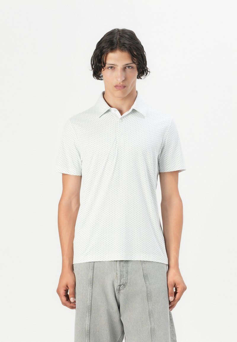 Polo de manga corta en gris claro con un patrón geométrico, fabricado en una tela suave. Presenta un collar y una tapeta de botones.